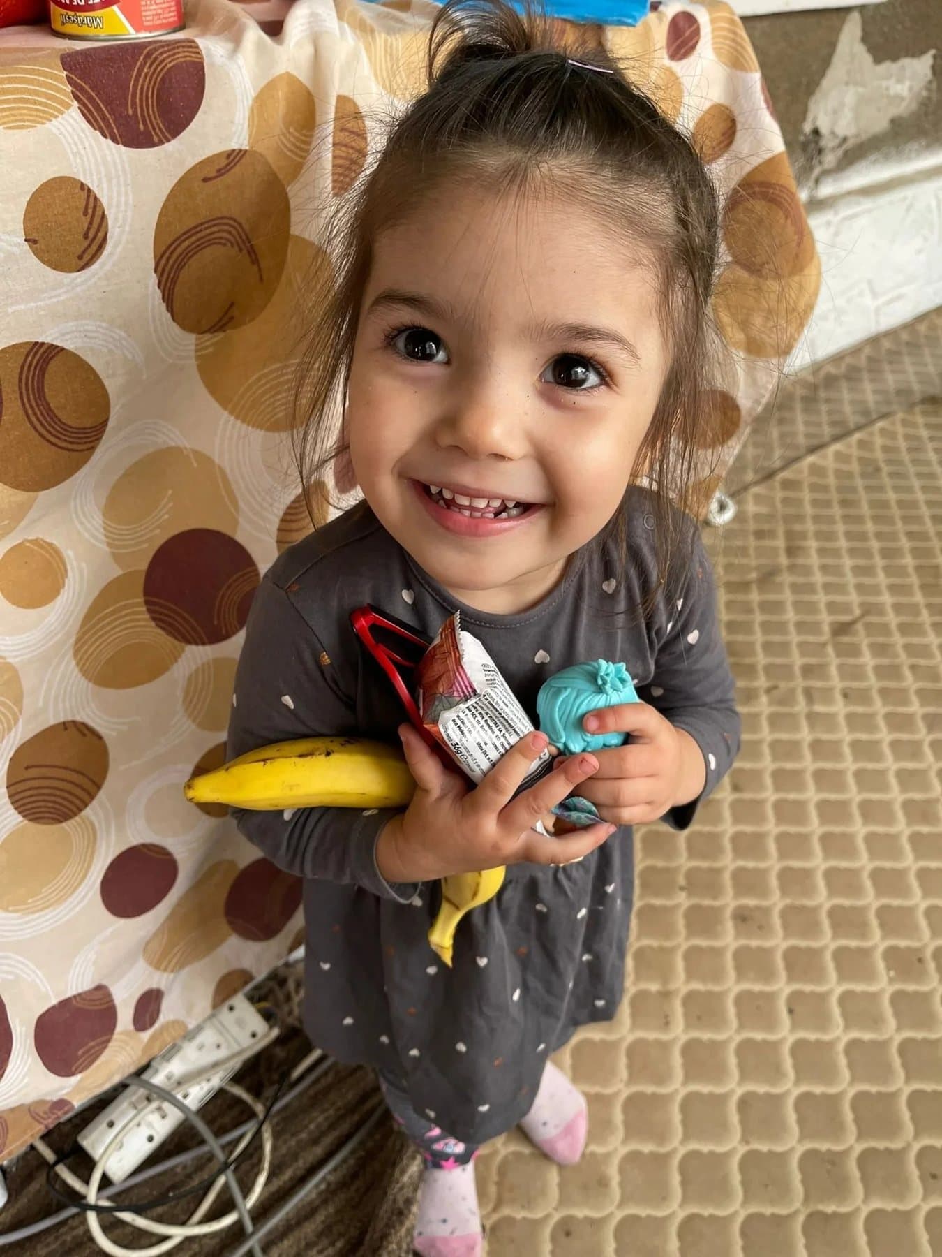 A smiling little girl holding snacks