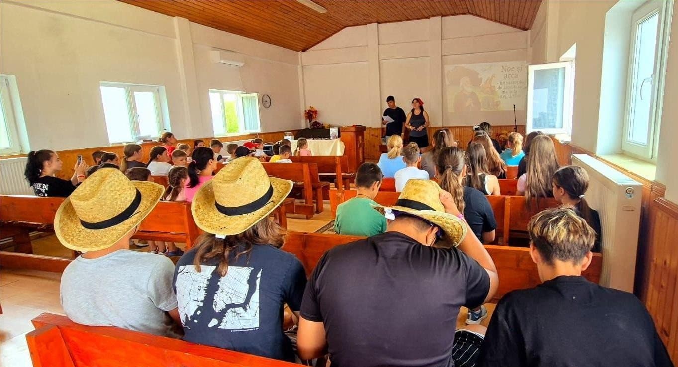 Children gathered in church wearing straw hats